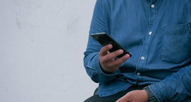 Man holding phone blue shirt and pants