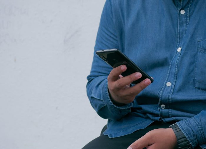 Man holding phone blue shirt and pants