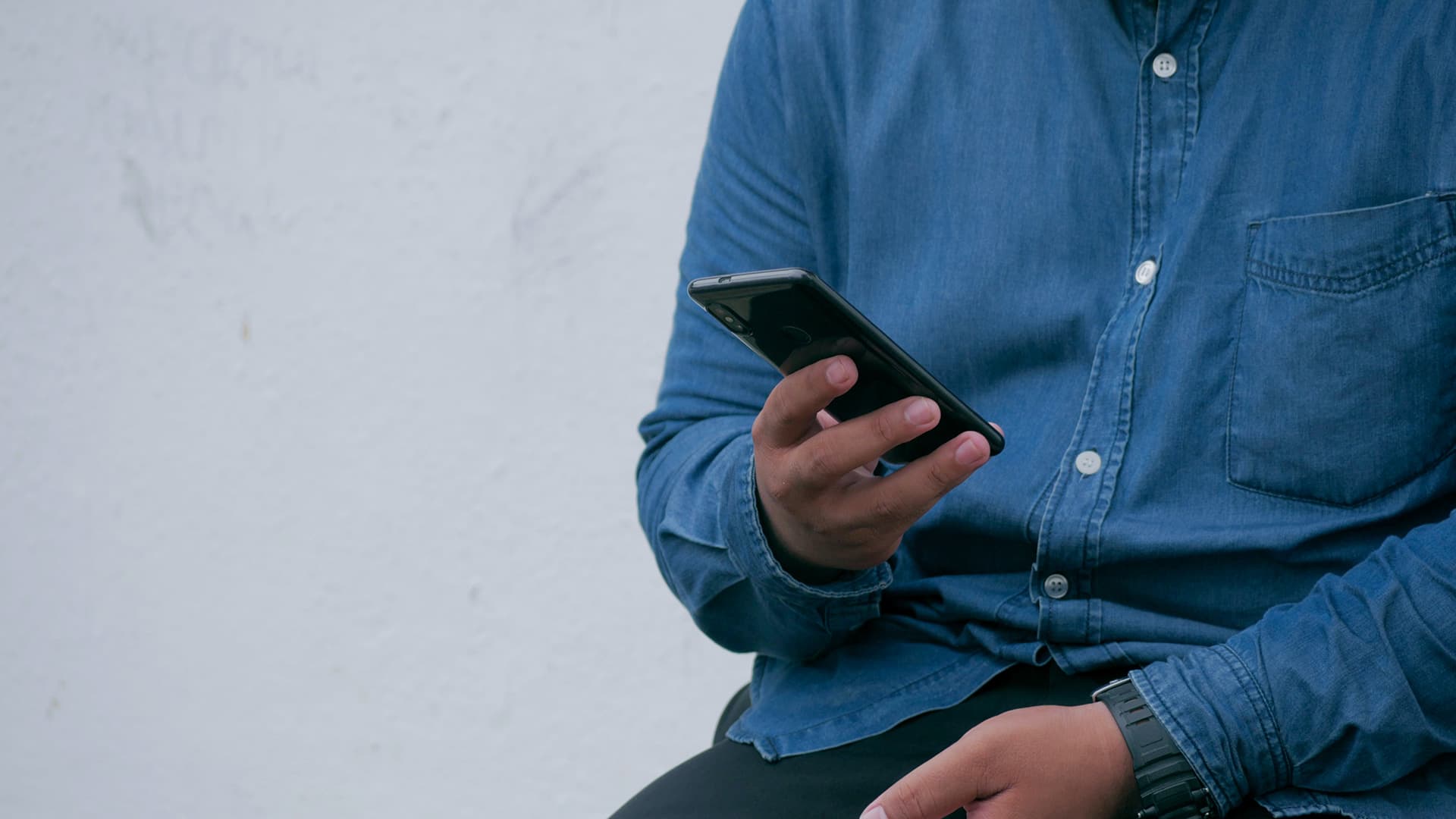 Man holding phone blue shirt and pants