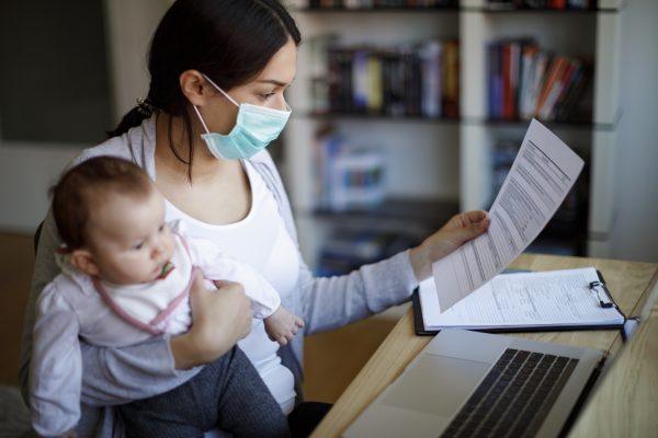 Mother with face protective mask working from home
